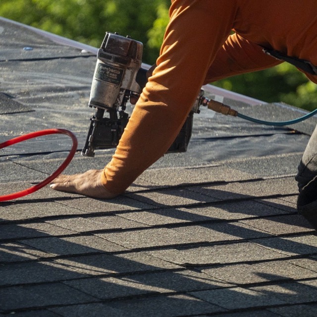Shingles going on: A crew member fastening new architectural shingles course by course.