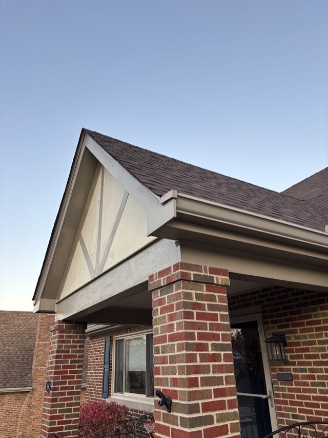 Gable and trim detail: Clean lines where the new roof meets the gable trim over a brick-column porch.